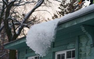 Big patch of snow being pushed off the roof with shovel